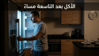 رجل متعب يفتح الثلاجة ليلاً في مطبخ مظلم مع عقارب الساعة تشير إلى العاشرة والنصف