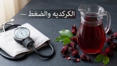 إبريق زجاجي مليء بمشروب الكركديه الأحمر بجانب جهاز قياس ضغط الدم على سطح داكن