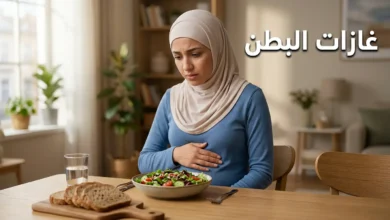صورة غلاف لمقال طبي عن غازات البطن تُظهر امرأة شابة تضع يدها على بطنها بجانب وجبة صحية على طاولة طعام