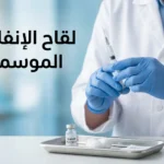 صورة غلاف تُظهر يد متخصص رعاية صحية يرتدي قفازات طبية زرقاء يحمل حقنة لقاح الإنفلونزا الموسمية بجانب قارورة اللقاح على صينية طبية في عيادة حديثة