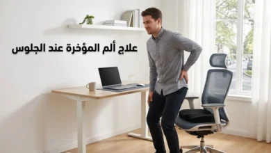 رجل يقف من كرسي مكتبه الأرغونومي وهو يضع يده على مؤخرته بألم خفيف مع وسادة عصعص طبية على الكرسي وعنوان علاج ألم المؤخرة عند الجلوس