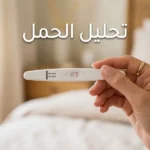 يد تمسك شريط اختبار حمل منزلي يُظهر نتيجة إيجابية بخطين وردييْن