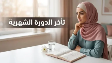 امرأة عربية شابة تتأمل تقويمها الصحي بجانب نافذة مضاءة بضوء طبيعي دافئ، في مشهد يرمز إلى متابعة الدورة الشهرية كعلامة حيوية.